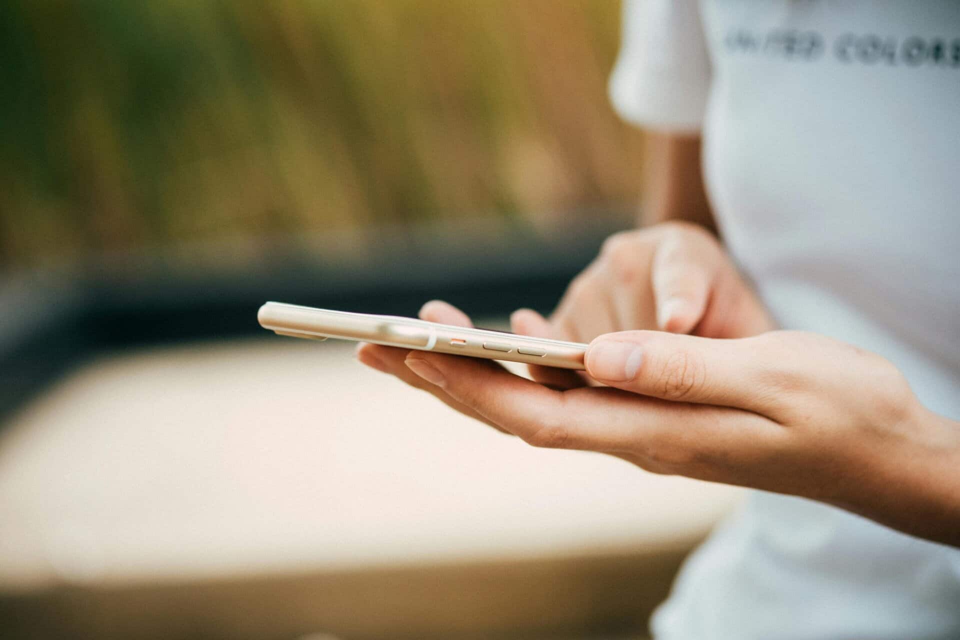 A person holding a smartphone in one hand and touching its screen with the other