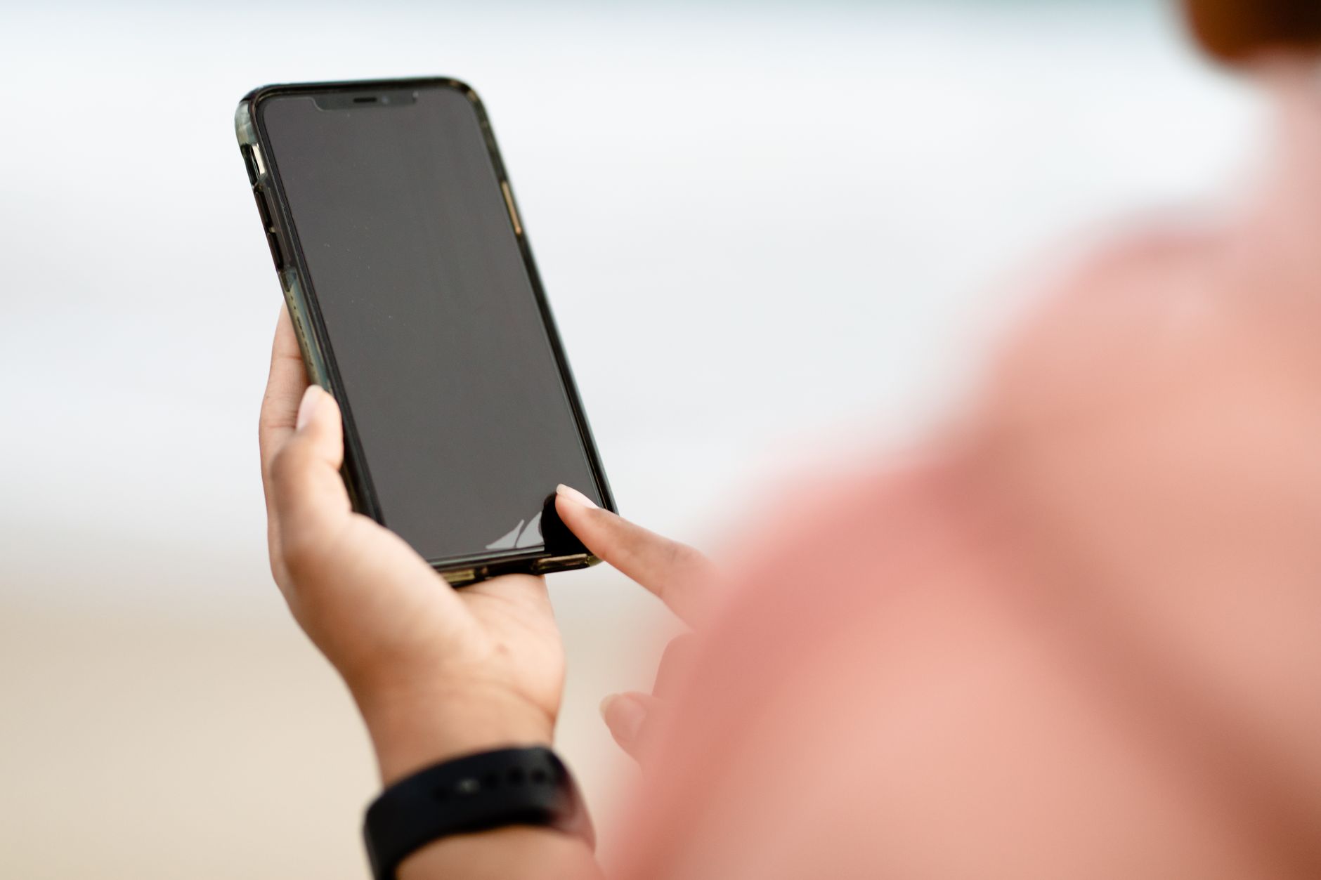 A hand interacting with a smartphone touchscreen outdoors. Modern technology concept.