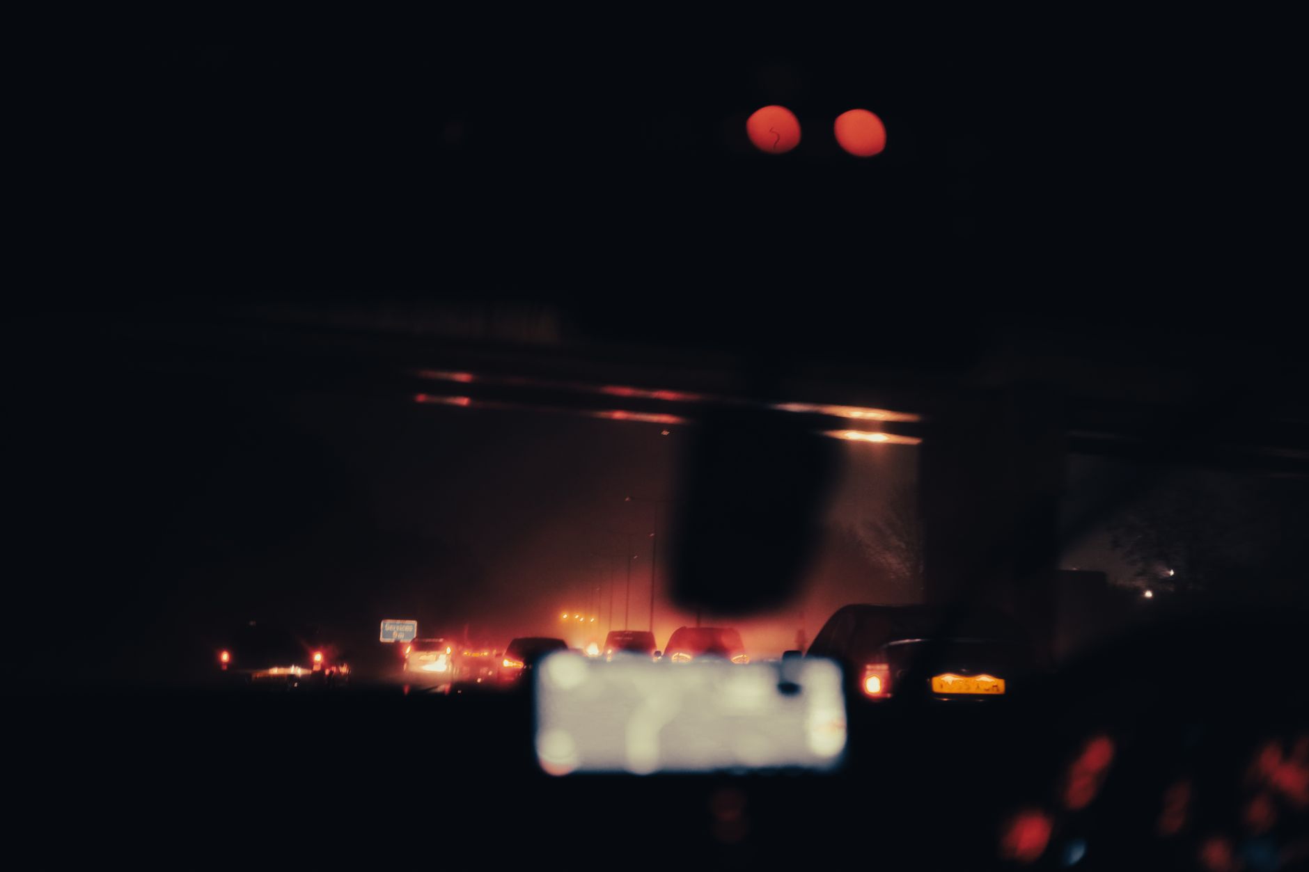 Blurred view of vehicles and car lights on a highway at night, creating a moody and illuminated atmosphere.